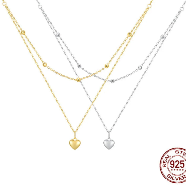 Double-layer heart pendant necklaces in 925 sterling silver with gold-tone and silver finishes, featuring beaded station chains on a white background — OmniVivo