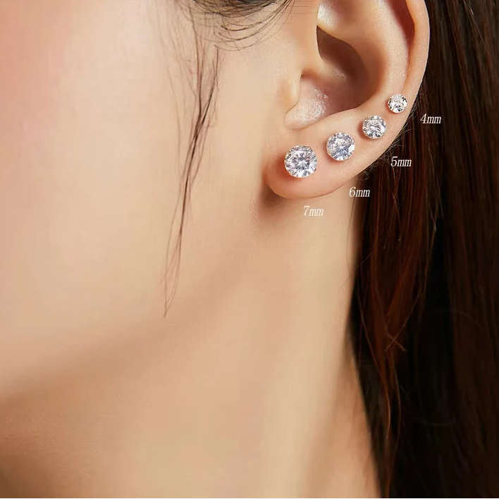 Close-up of an ear wearing platinum-plated 925 sterling silver CZ stud earrings in multiple sizes 4mm–7mm, polished shine — OmniVivo