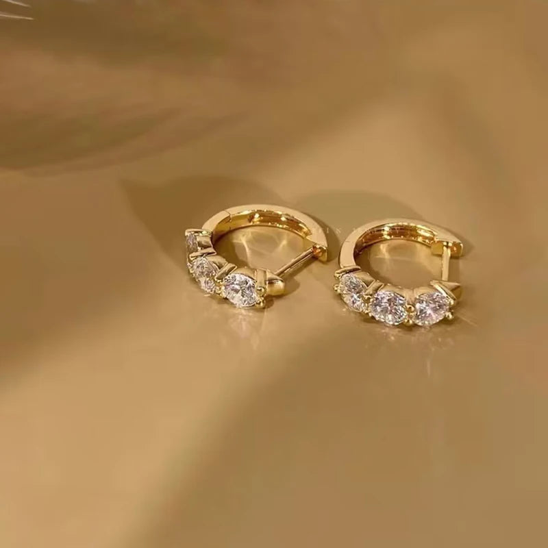 sterling silver hoop earrings plated in 14K yellow gold, set with round-cut D color VVS1 moissanite (2.5–4 mm), lifestyle photo on beige fabric — OmniVivo