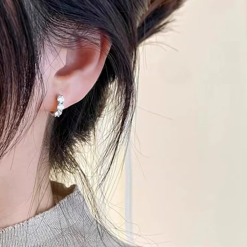 sterling silver hoop earrings plated in 14K yellow gold, featuring round-cut D color VVS1 moissanite (2.5–4 mm), shown worn on ear close-up — OmniVivo