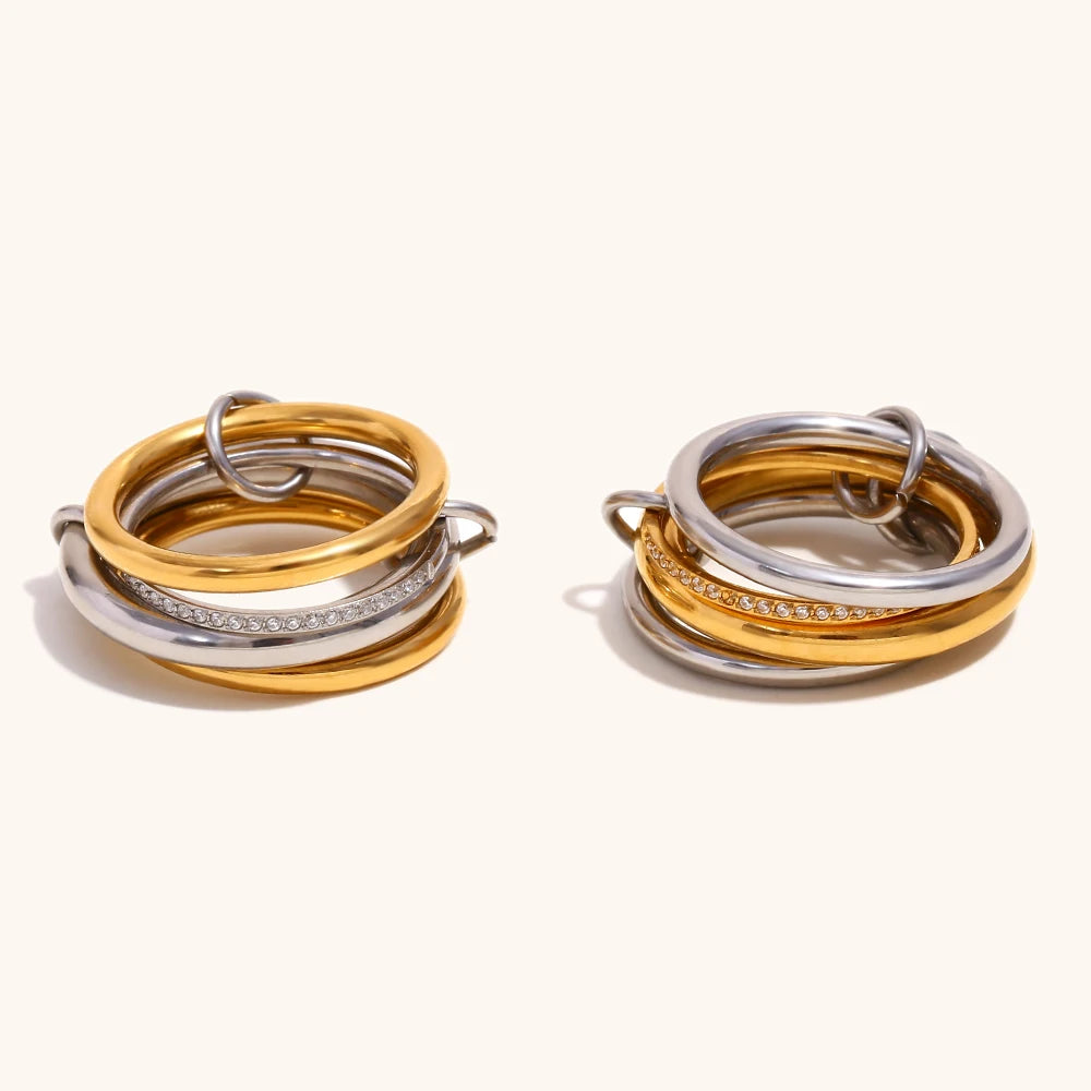 Two NeoVox multi-layer statement rings displayed side-by-side, each featuring a dynamic blend of polished gold and silver-toned bands, one with a sparkling zircon accent band, showcasing their versatile and stackable design.