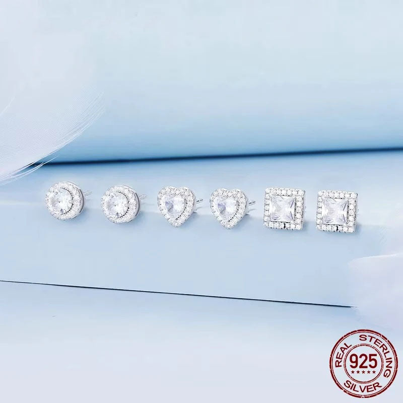 A sparkling collection of Serena Halo CZ Stud Earrings in 925 sterling silver, showcasing three elegant shapes: round, heart, and square, each featuring a brilliant central cubic zirconia stone encircled by a micro-pavé halo.
