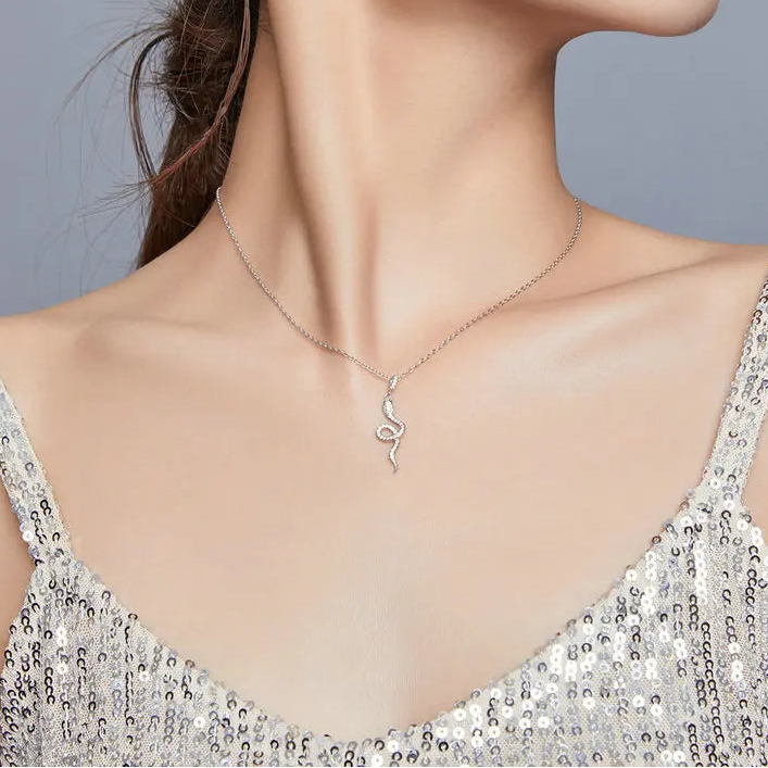 925 sterling silver snake pendant necklace with pavé CZ and green eye accent, shown on model for scale with sequin top against a neutral backdrop — OmniVivo