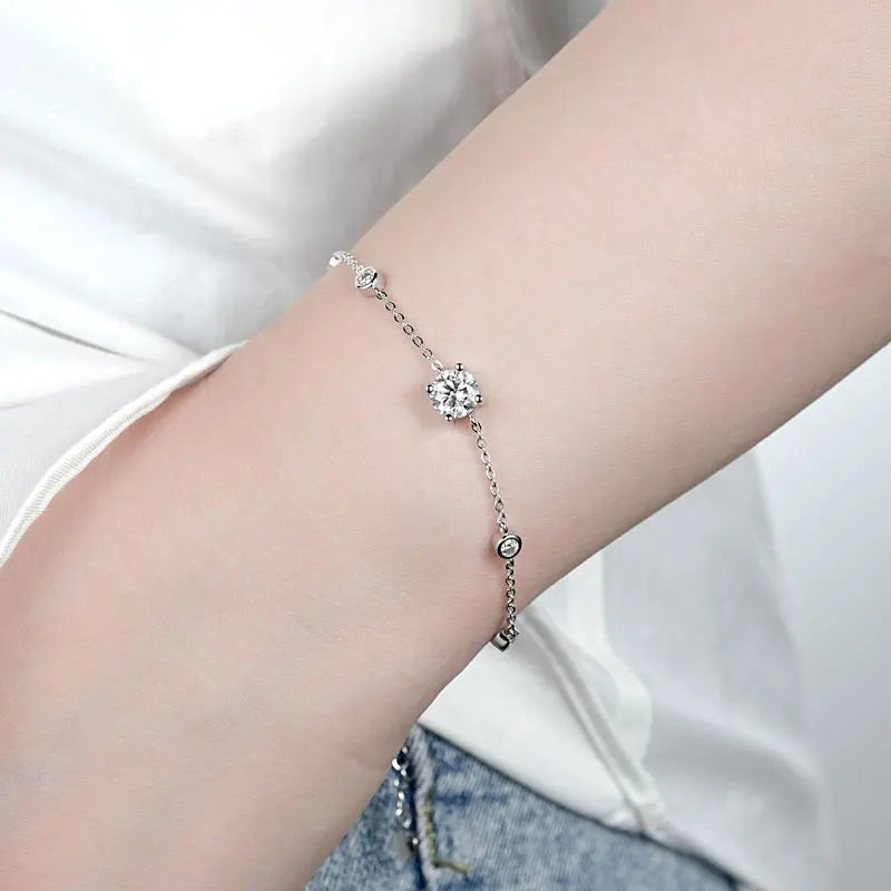 On-wrist photo of a 925 sterling silver moissanite bracelet with a 6.5 mm center stone and 2.5 mm bezel accents, adjustable 16.5+5 cm chain, D–E color VVS1 — OmniVivo