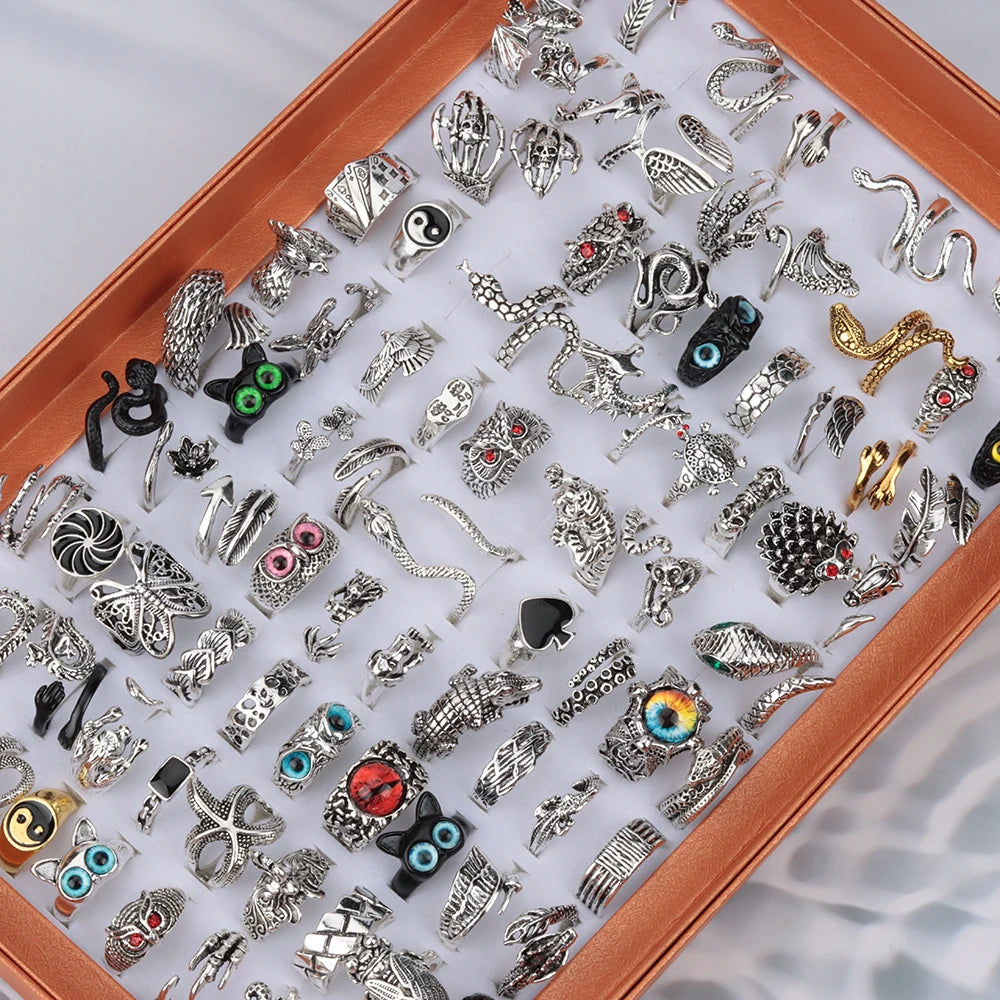 Assorted vintage punk adjustable rings set with snake, dragon, evil eye and gothic motifs displayed in a white tray — OmniVivo