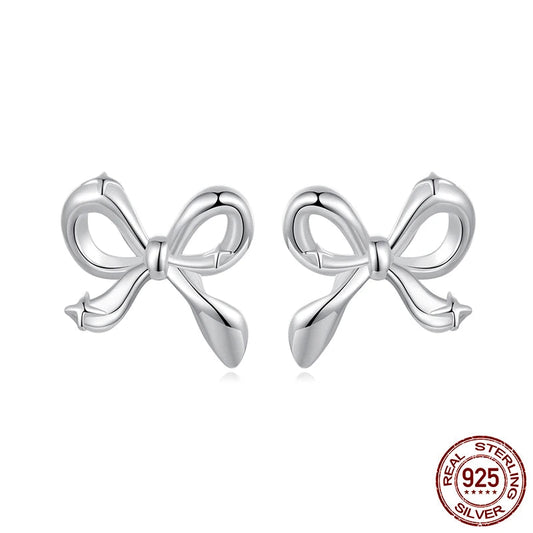 Close-up of mini bow stud earrings in 925 sterling silver with white-gold plating, ribbon knot design on white background — OmniVivo