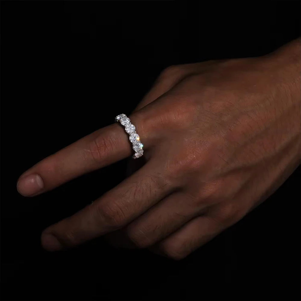 Hand wearing a 5 mm D-color VVS1 moissanite eternity row ring in solid 925 sterling silver, prong-set round stones, high-polish band on a dark background — OmniVivo