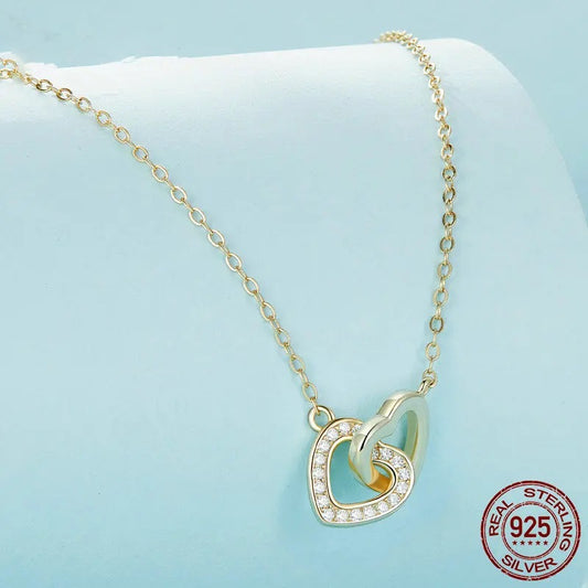 An elegant Amira Interlocked Hearts Necklace in gold tone, featuring a beautiful 3D interlocking heart pendant, with one heart adorned with sparkling cubic zirconia, symbolizing endless connection and love.