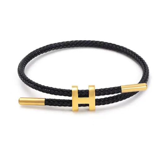 Black braided rope bracelet with sleek gold bar clasp, minimalist unisex design, lightweight and stackable, studio shot on clean white background — OmniVivo