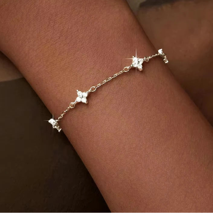 Gold-plated 925 sterling silver CZ flower bracelet on wrist, delicate chain with pavé charms, warm indoor lighting — OmniVivo