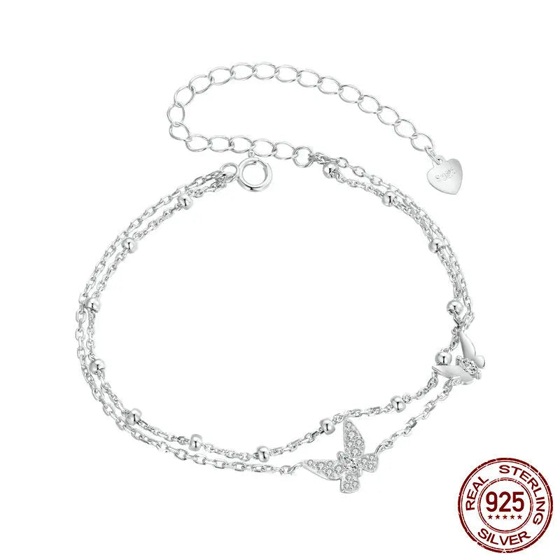 Double-layer butterfly bracelet in genuine 925 sterling silver with pavé CZ, dainty beaded layered chains and adjustable extender, studio shot on clean white background — OmniVivo