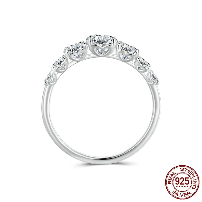 Side profile of a 925 sterling silver moissanite heart-setting ring with graduated round stones across the band, D color VVS1 EX brilliance, prong-set half-eternity design — OmniVivo