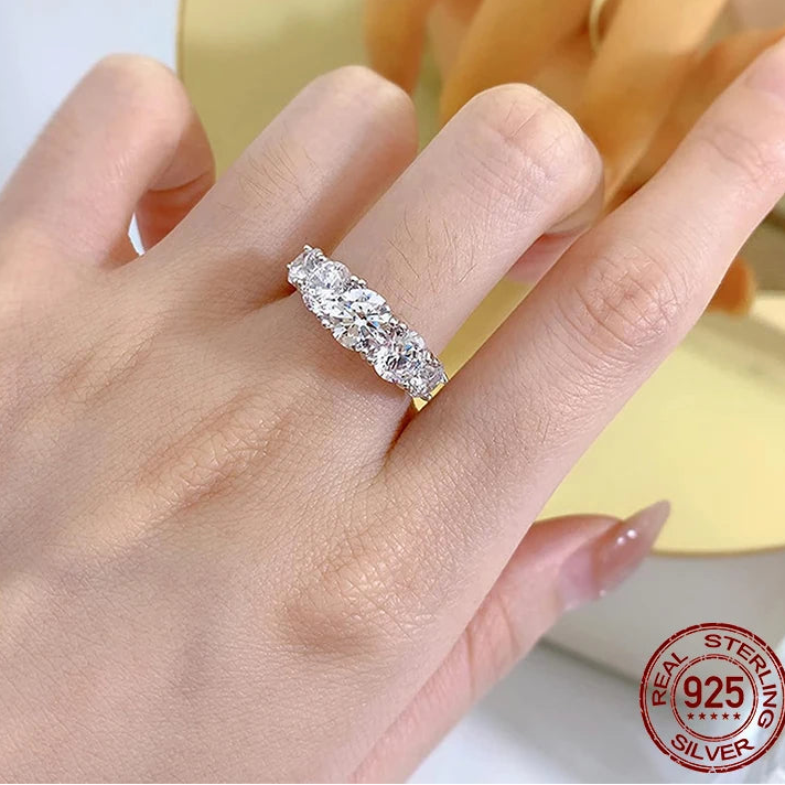 Close-up of D color VVS1 EX lab moissanite ring in 925 sterling silver, prong-set graduated round stones creating a bright half-eternity sparkle, worn on hand in lifestyle scene — OmniVivo