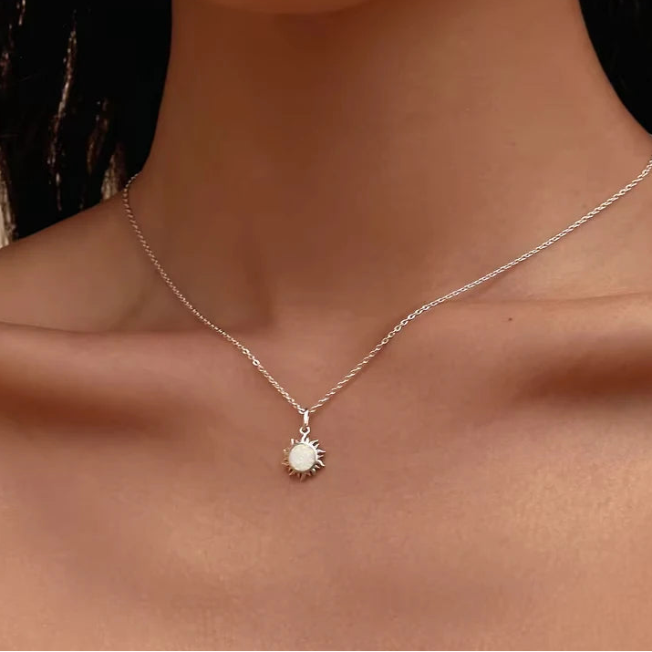 Model wearing white opal sun pendant necklace in platinum-plated 925 sterling silver, delicate chain on neck, warm studio lighting — OmniVivo