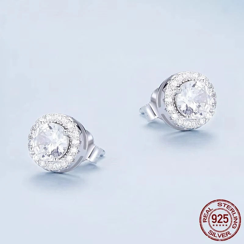 A sparkling pair of Serena Halo CZ Stud Earrings in 925 sterling silver, featuring a brilliant central cubic zirconia stone encircled by a micro-pavé halo, showcasing their celestial elegance and radiant design.