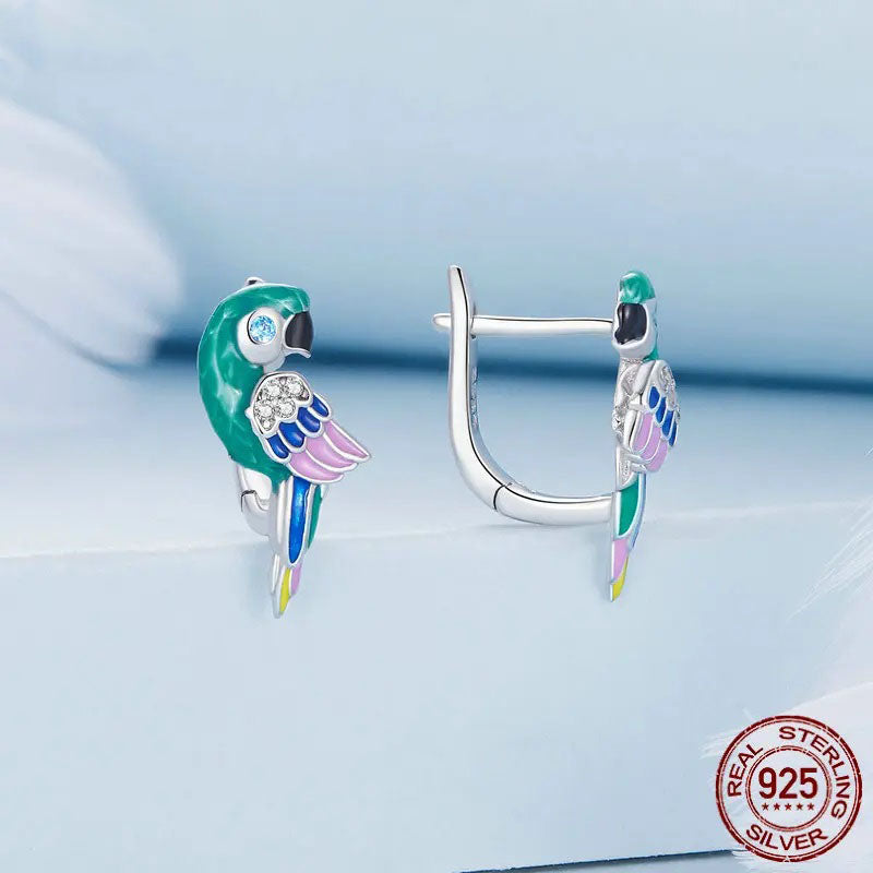 A vibrant pair of sterling silver parrot-shaped hoop earrings, adorned with brilliant green, pink, blue, and yellow enamel, featuring sparkling cubic zirconia details for a playful yet elegant look.