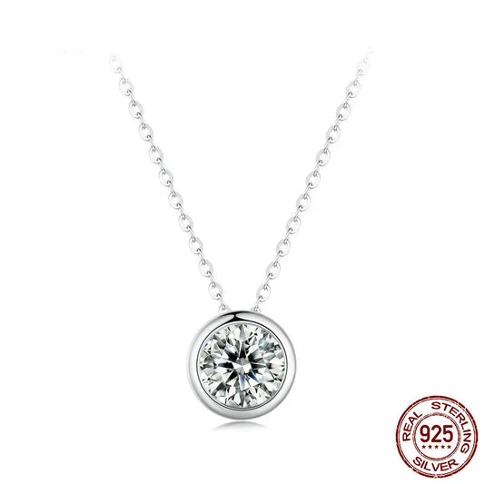 An elegant Thalassa silver-toned necklace featuring a dazzling round moissanite stone securely set in a classic bezel setting on a delicate chain, highlighting its brilliant sparkle.
