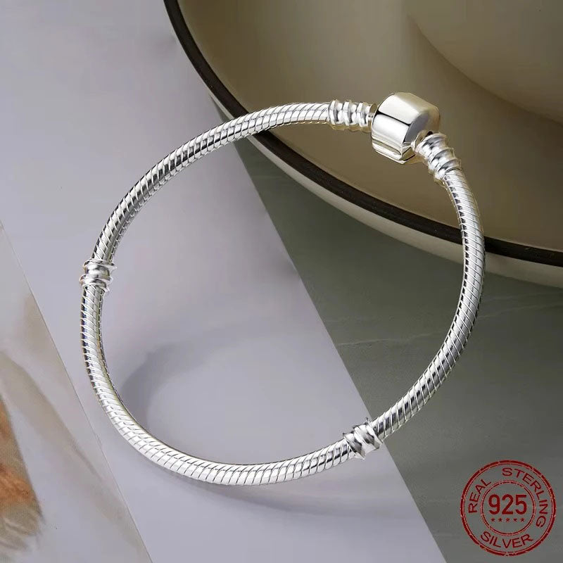 Elegant Vespera 925 sterling silver snake chain bracelet, featuring a smooth, high-polish finish and a secure barrel clasp with bead details, beautifully displayed on a light-colored, textured surface.