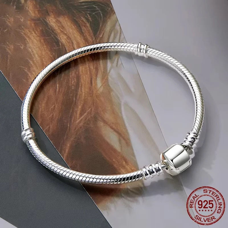 Elegant Vespera 925 sterling silver snake chain bracelet, featuring a smooth, high-polish finish and a secure barrel clasp with bead details, beautifully displayed on a magazine or textured surface.