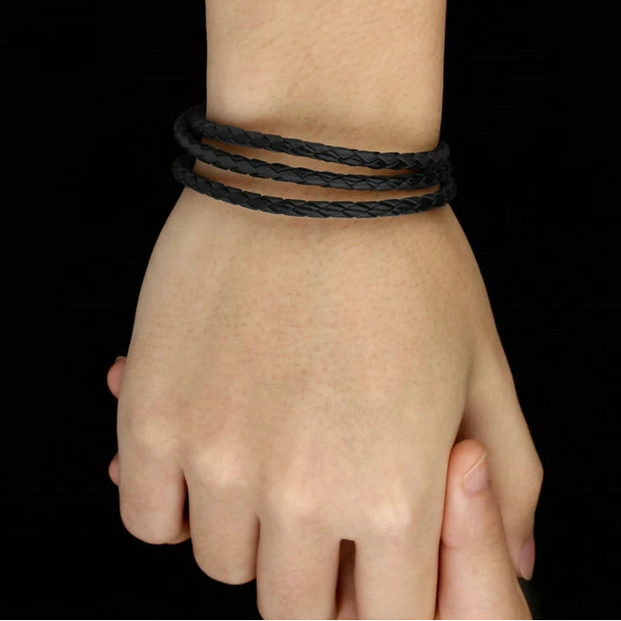 Hand wearing a black braided PU leather multi-layer wrap bracelet with magnetic clasp, 60 cm adjustable, on a black background — OmniVivo