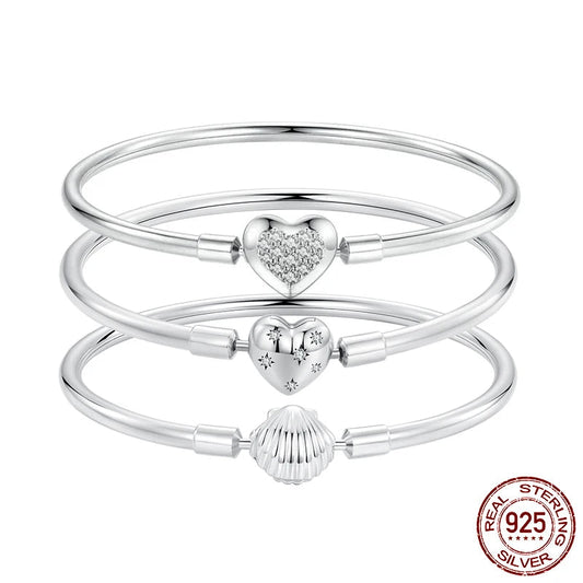 Set of three 925 sterling silver charm bangle bracelets with heart, bead, and shell clasps on a white background — OmniVivo