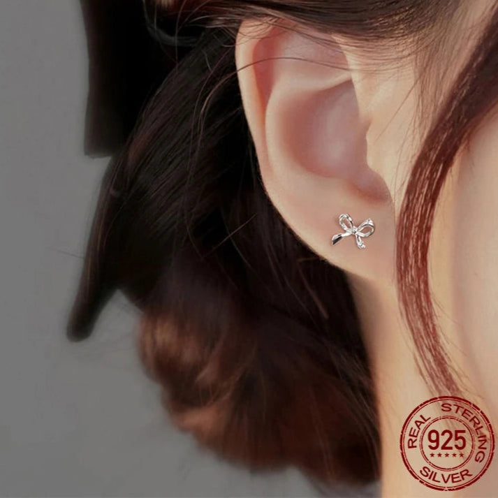 Close-up of 925 sterling silver bow stud earring, white gold plated, worn on ear