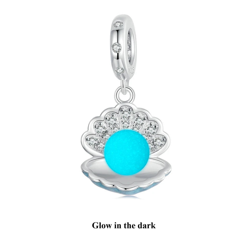 Glow-in-the-dark sterling silver charm with floral design and zircon accent, shown on black & white split background — OmniVivo