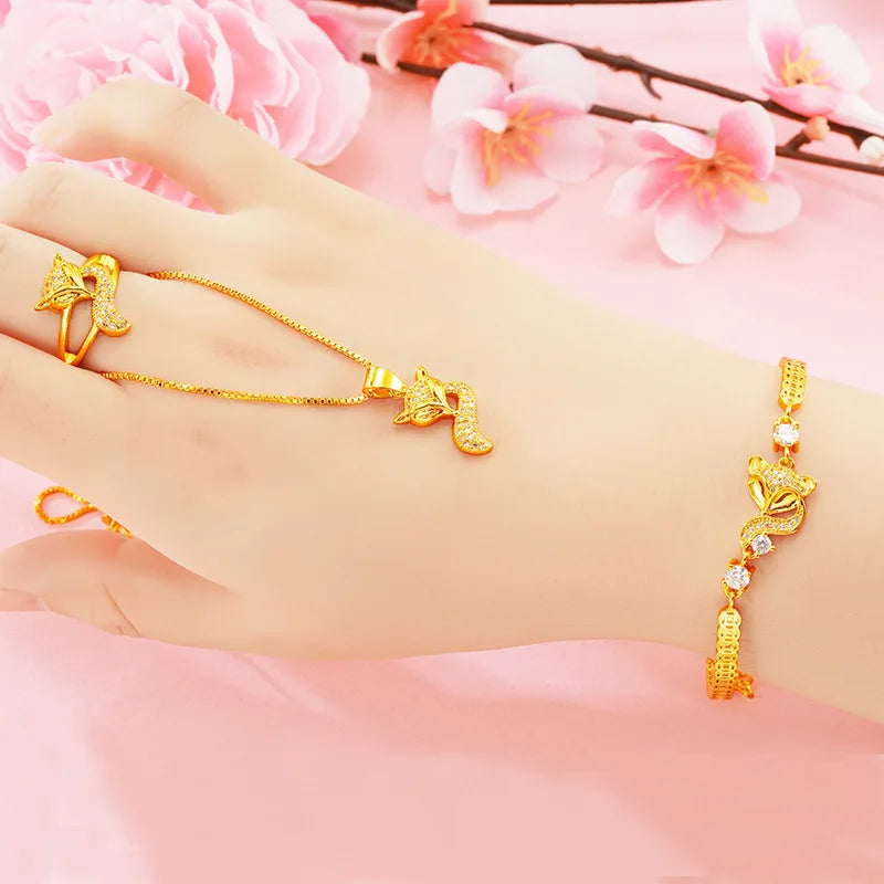 24K (9999) pure gold fox jewelry set—necklace, ring, and bracelet—shown on a hand with a pink floral background.