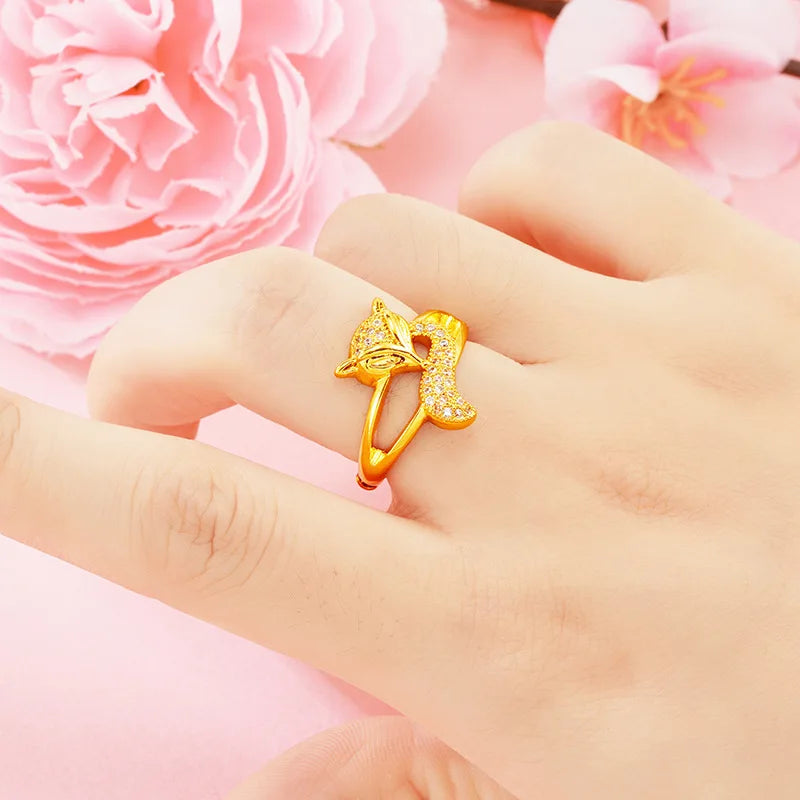 24K (9999) pure gold fox ring with zircon accents, worn on hand — pink floral background.