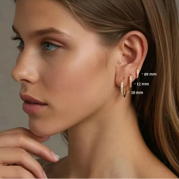 Close-up of a model wearing OmniVivo gold-plated 925 sterling silver CZ huggie hoop earrings in 9 mm, 12 mm, and 18 mm sizes—stacked lobe/cartilage look with pavé cubic zirconia sparkle.