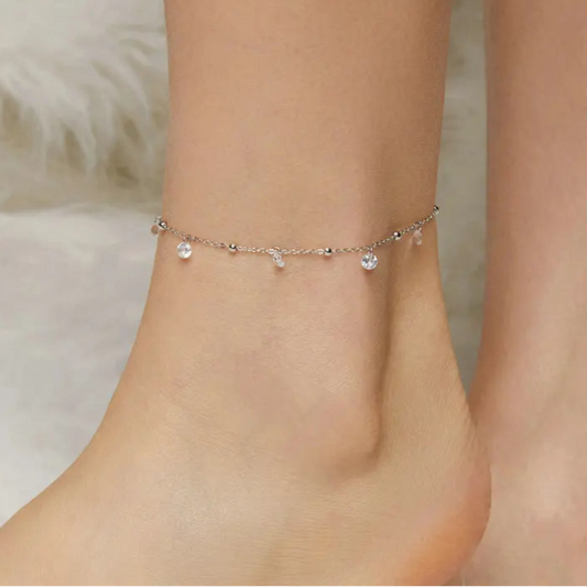 925 sterling silver cubic zirconia anklet with adjustable chain and dangle charms, worn on ankle — close-up.