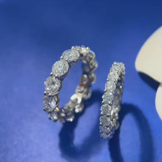 Product video—5 mm D-color VVS1 moissanite row/eternity ring in solid 925 sterling silver, prong-set round stones on blue background, high-polish finish — OmniVivo