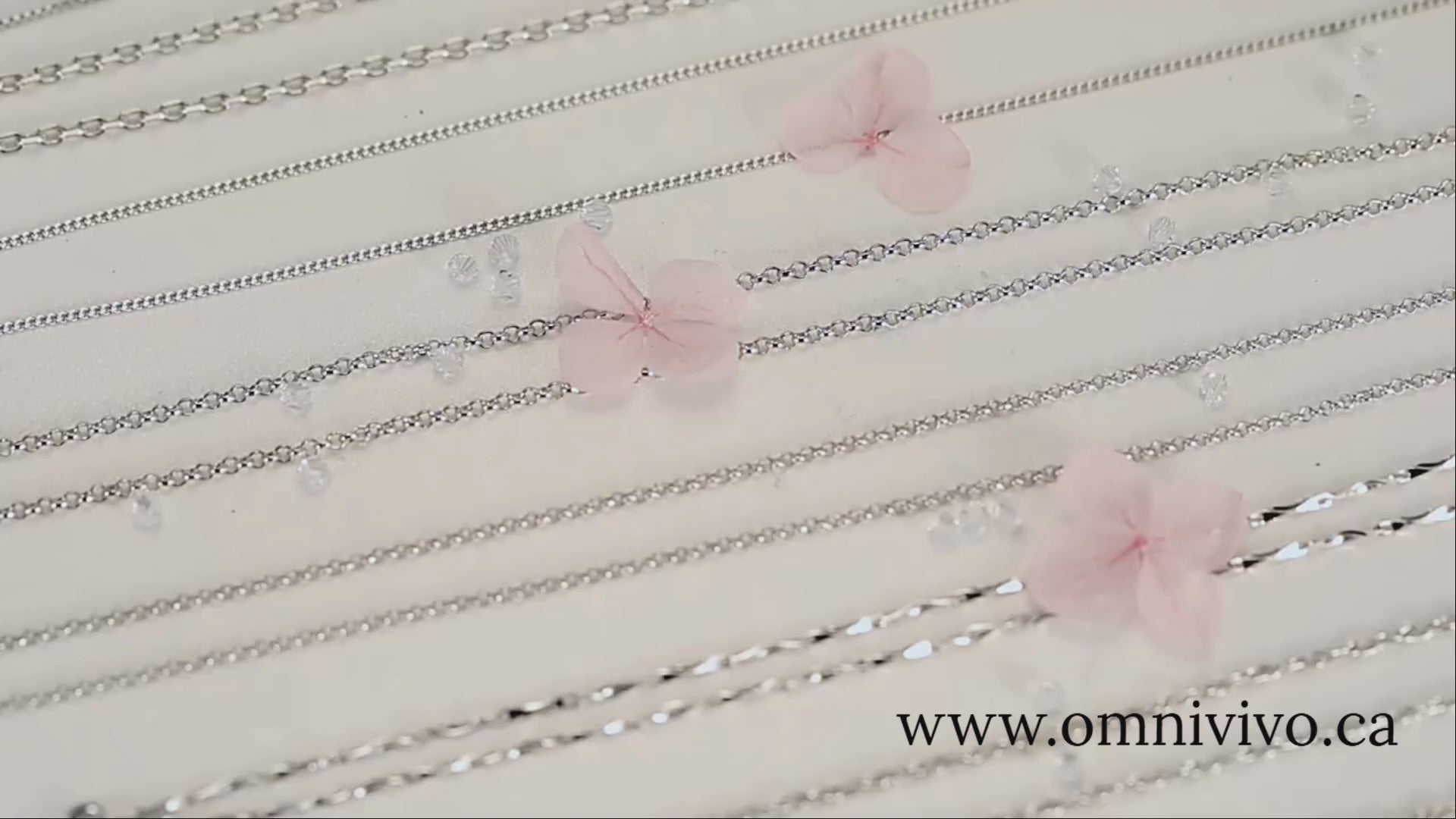 Assorted 925 sterling silver necklace chains with lobster/O-link styles, studio flat-lay on a soft floral backdrop — OmniVivo