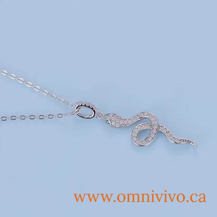 Product video—925 sterling silver snake pendant necklace with pavé CZ and green eye accents on light-blue background, adjustable link chain — OmniVivo