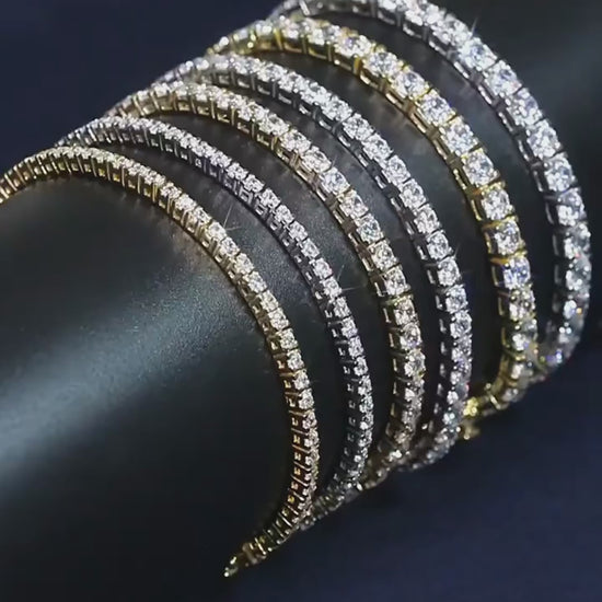Rotating video of moissanite tennis bracelets stacked in 925 sterling silver and gold tone on a black display roll — OmniVivo