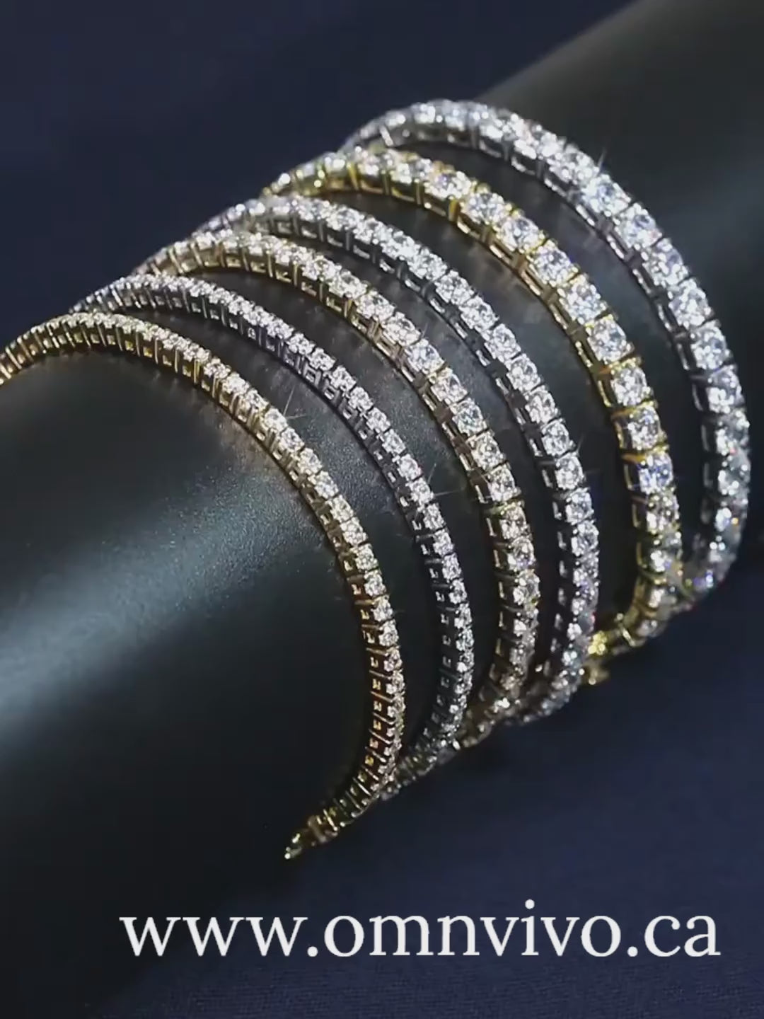 Rotating video of moissanite tennis bracelets stacked in 925 sterling silver and gold tone on a black display roll — OmniVivo